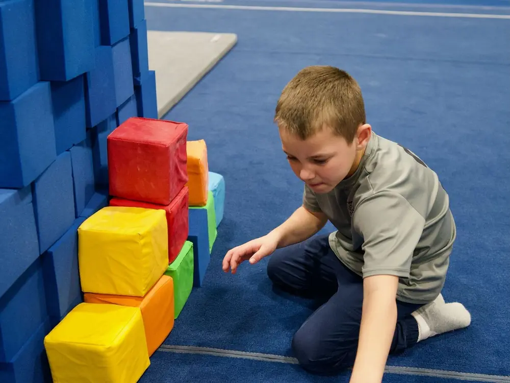 A camper stacking colorful foam blocks into a tower