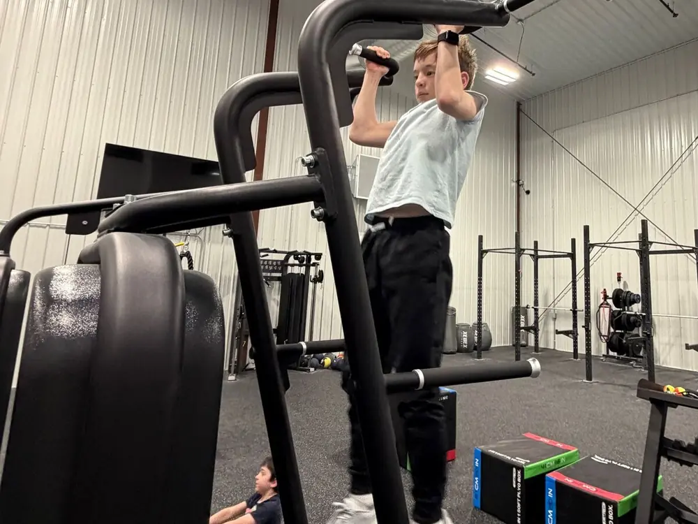 A teen doing pull-ups on the bar in the Fitness Zone
