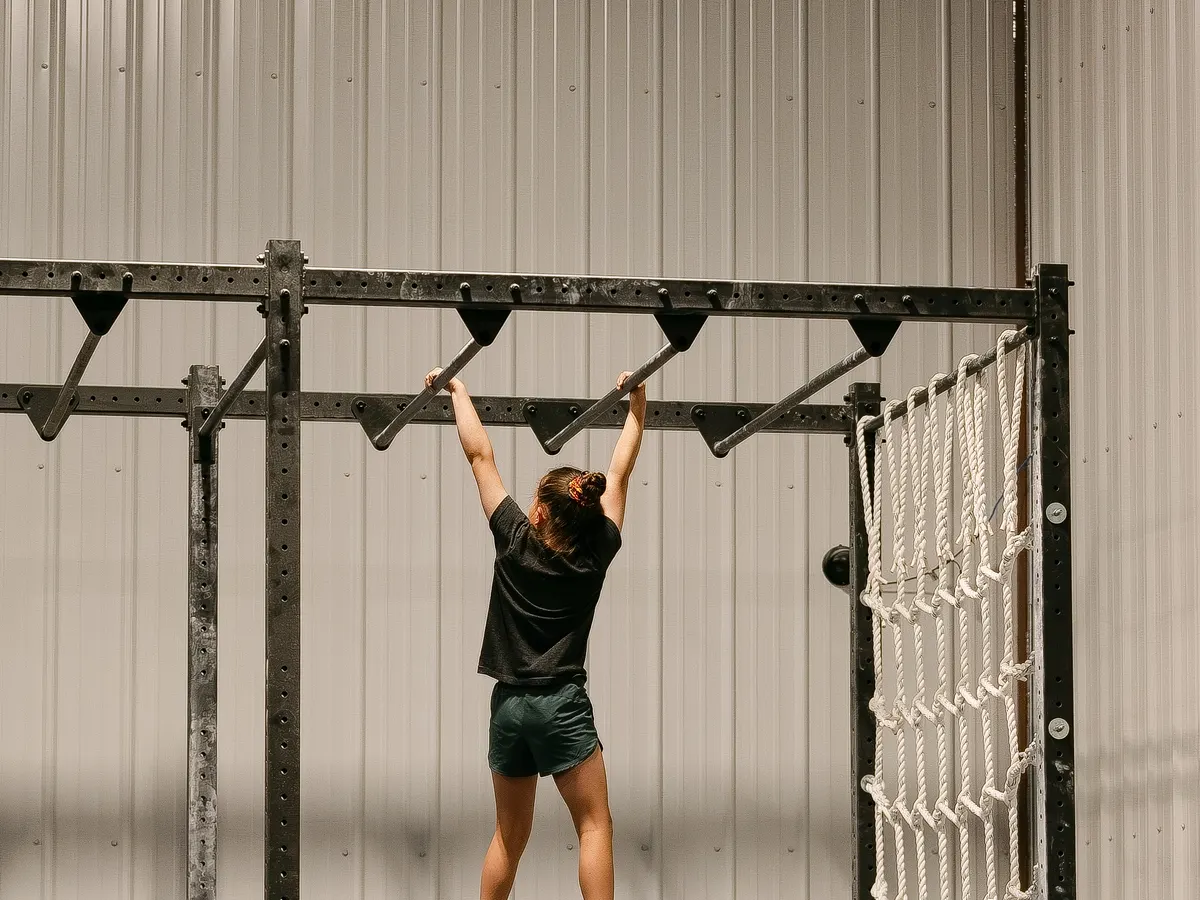 A kid hanging from the monkey bars on the 50-foot Ninja rig, beside the climbing net