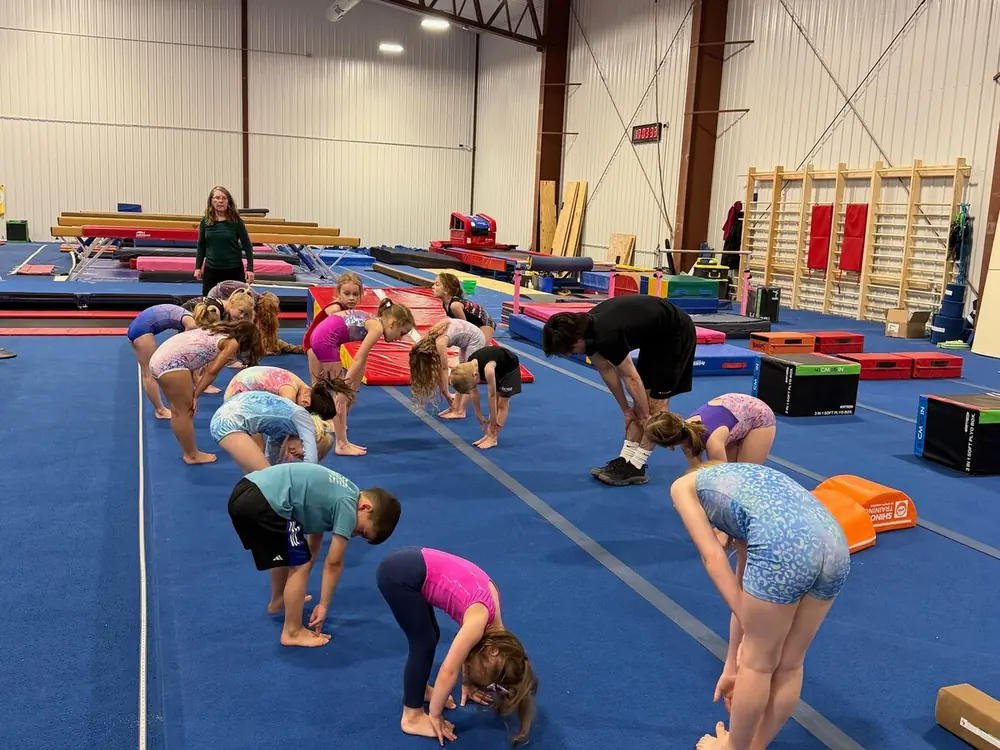 Kids stretching in rows on the blue mats during warm-up