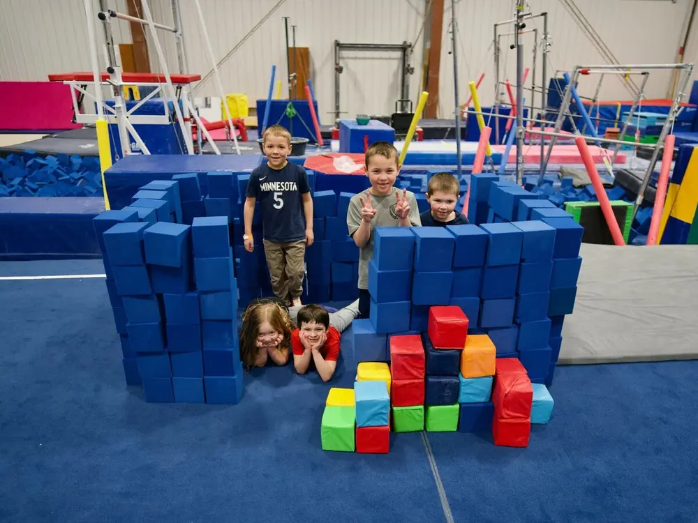 Campers peeking over a fort of blue foam blocks