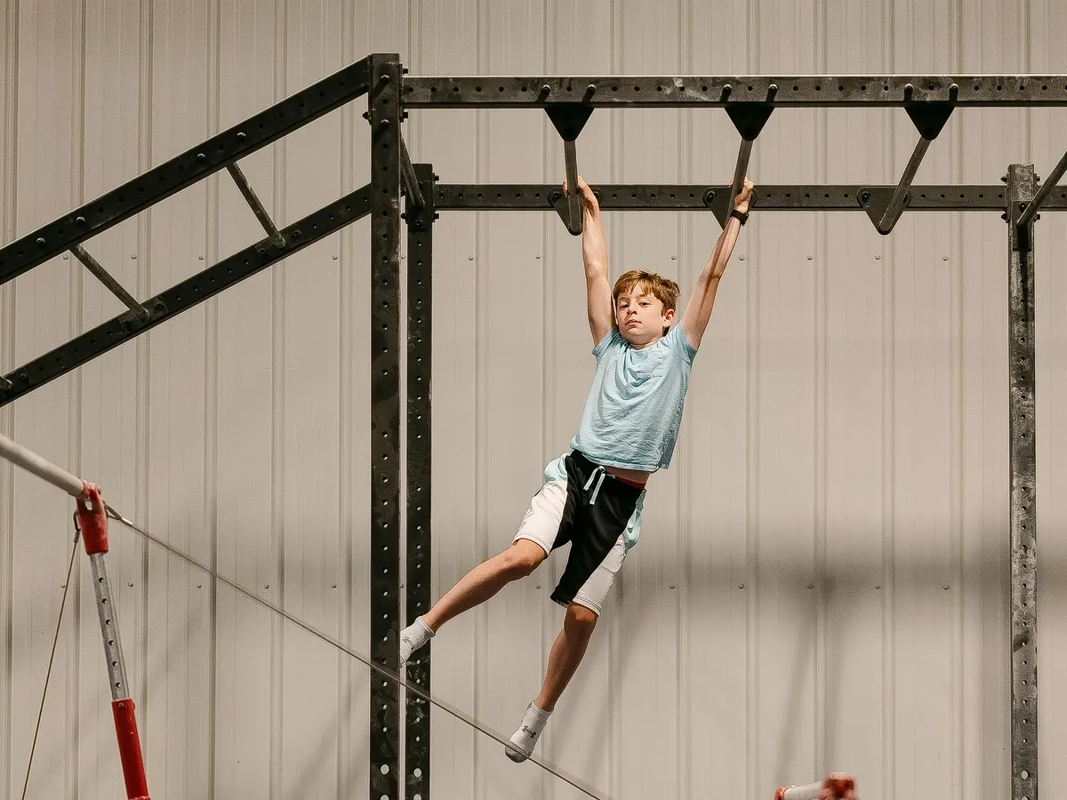 A boy swinging along the monkey bars of the Ninja rig